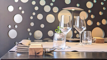 Elegant dining setup with glassware and modern decor at a restaurant in the evening. Side view with copy space