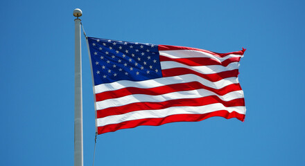 Obraz premium American flag waving against a clear blue sky on a flagpole with a spherical finial on top
