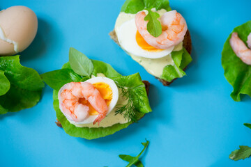 Sandwich with egg and shrimp on blue background from above