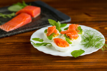 Appetizer of boiled eggs and lightly salted salmon with dill