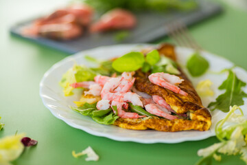 Serving omelette with shrimps on a green background