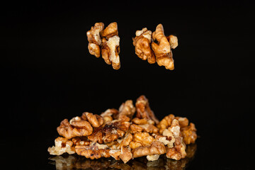 a handful of peeled walnuts on a black background