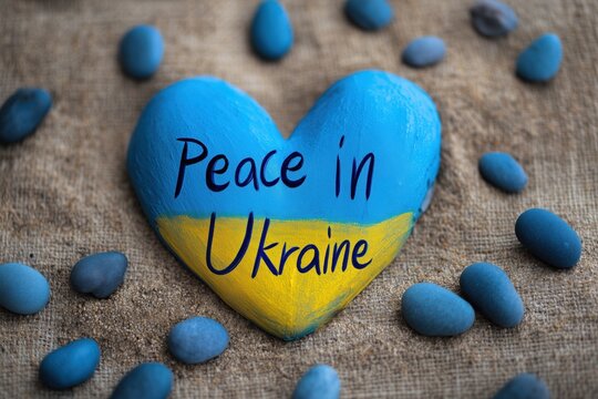 Heart shaped stone with peace message for Ukraine, symbolizing hope, solidarity, and support on neutral backdrop.