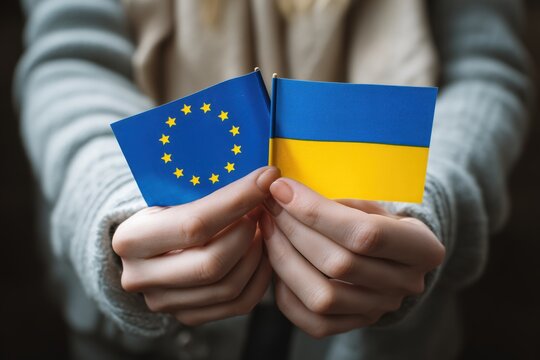 Hands hold the flags of Ukraine and the European Union, symbolizing support, solidarity, and unity in difficult times.