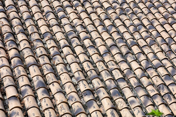 Close-up view of traditional clay roof tiles arranged in uniform rows, showing weathered textures,...