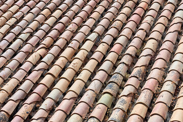 Close-up of weathered terracotta roof tiles arranged in neat, repetitive rows, showing varied earthy tones and aged textures under sunlight; roof, texture;