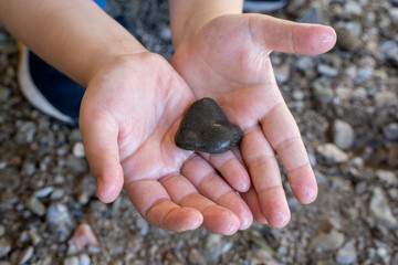 Child holding wet heart shaped stone in hands