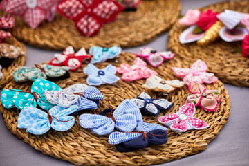 Handmade fabric bows and butterflies in various colors and patterns are arranged on round straw...