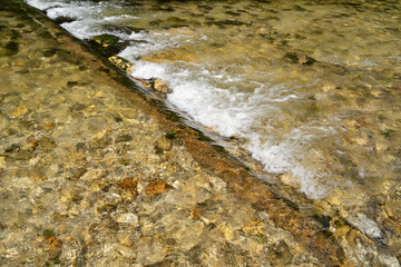 Cold and clear river water flowing over rocks 
