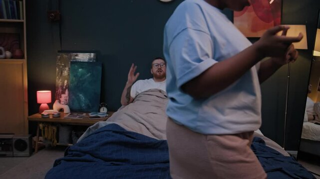 Unrecognizable Black woman walking back and forth in bedroom, nagging her Caucasian husband