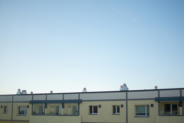 Rooftop ventilation pipes and chimneys on a modern residential building under a clear evening sky