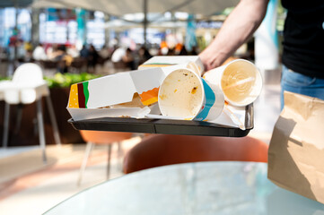 Fast food tray being cleaned after a meal in a public food court, reflecting responsible personal behavior and modern consumption culture