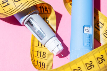 Flat lay of two Ozempic pens on a pink background. Concept of diabetes treatment, weight loss...