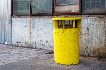 bright yellow ventilation outlet stands against an old, worn-out wall with mosaic tiles