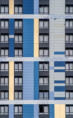 Obraz premium A building exterior with alternating blue, yellow, and gray panels arranged in geometric patterns
