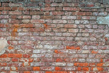 Old weathered brick wall with uneven colors, showcasing red and brown bricks