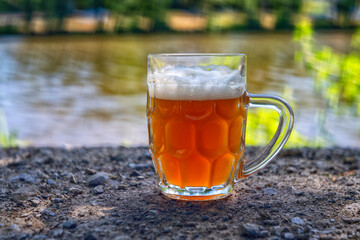 White beer in a glass on the river bank