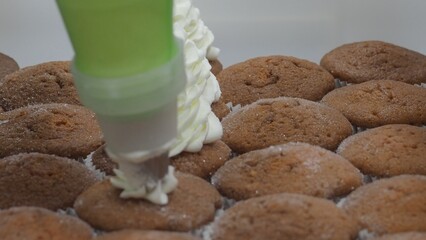 Pastry professional piping creamy frosting onto golden muffins, creating delectable culinary...