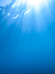 Light filtering down through blue water. Underwater sunlight in deep sea. Light viewed from blue abyss. Underwater sunlight shining deep under water with ripples on wave surface ocean ray, crystal.