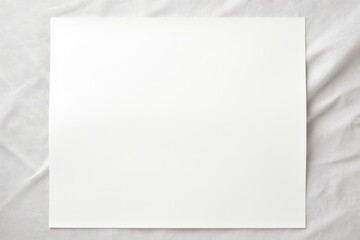White blank sheet of paper resting on a textured gray fabric background, creating a minimalist backdrop for design or presentation