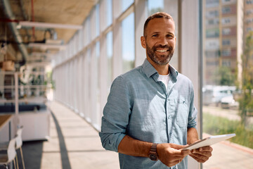 Happy businessman with digital tablet in the office looking at camera.