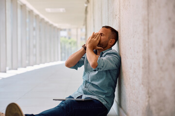 Male entrepreneur feeling exhausted after working on laptop in the office.