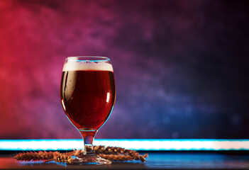 Glass of craft beer on table, colored neon background with copy space