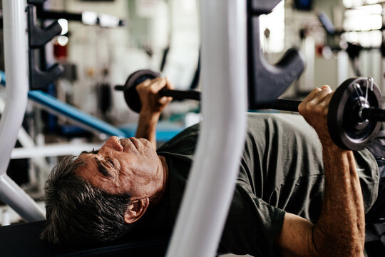 Senior man working out on a bench press in a gym, focused on strength training and healthy aging - Powered by Adobe