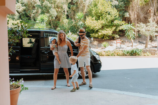 Parents with toddlers boarding car for airport transfer or holiday trip