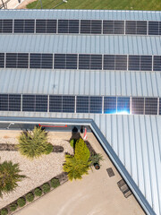 A rooftop with solar panels on a metallic structure, overlooking a landscaped area with plants,...