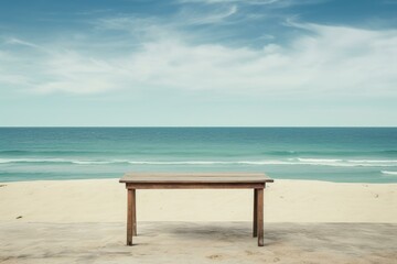 Fototapeta premium Empty wooden table stands on a beach with a beautiful ocean view, offering a serene and inviting scene