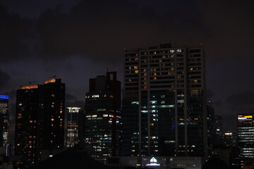Obraz premium Illuminated Cityscape at Night: Buildings Silhouetted Against a Dark Sky