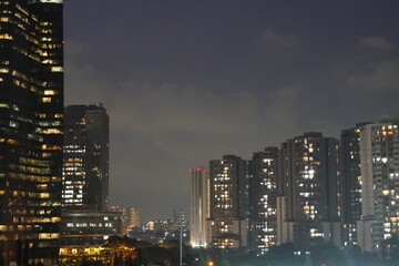 Obraz premium Nighttime Cityscape: Illuminated Towers and Dark Sky