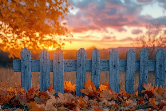 A rustic fence adorned with fallen leaves, bathed in the warm glow of a stunning autumn sunset.