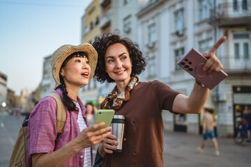 two women use mobile phone walk and touring city on vacation