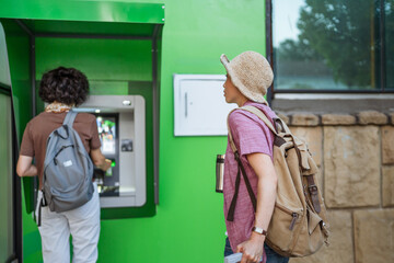 japanese woman tourist with luggage waiting in line at the ATM
