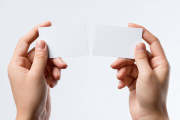 Obraz premium Two hands hold up blank rectangular white cards against a white background