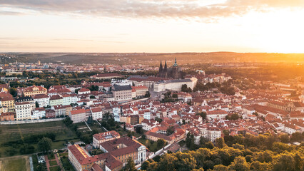 Golden sunrise casts warm light over Prague Castle, illuminating the historic buildings and...