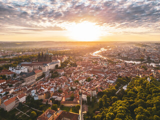 Fototapeta premium Breathtaking sunrise illuminates Prague Castle, casting a golden hue over the historic architecture and lush greenery. The city awakens beneath a colorful sky, revealing its charm.