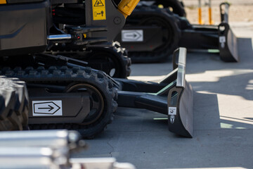 tracked construction vehicles with blade attachments on concrete surface, close up of heavy equipment with arrows and warning labels, industrial excavation and groundwork machinery display