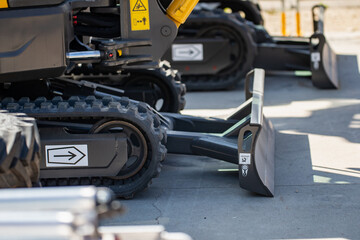 tracked construction vehicles with blade attachments on concrete surface, close up of heavy equipment with arrows and warning labels, industrial excavation and groundwork machinery display