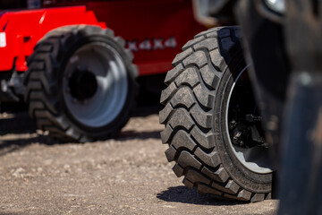 close-up of heavy-duty construction vehicle tires on dirt surface, industrial all-terrain wheels...