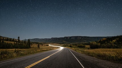 Road stretches through a landscape with distant mountains under a dark blue sky.