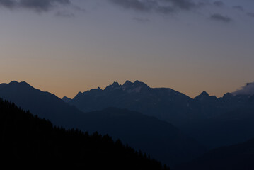 Majestic mountains glow with the last light of sunset, their peaks illuminated in warm hues against a twilight sky. This stunning scene evokes peacefulness and natural grandeur.
