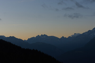 Majestic mountains glow with the last light of sunset, their peaks illuminated in warm hues against a twilight sky. This stunning scene evokes peacefulness and natural grandeur.