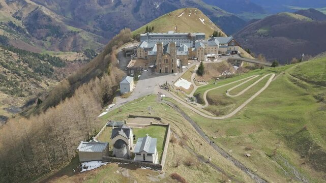 Panoramic view of the Basilica of Our Lady of La Salette in the French Alps, surrounded by lush forests and snow-covered mountains. Site of the 1846 Marian apparitions.