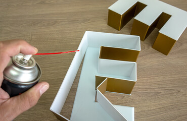 A three-dimensional letter made of plastic.Gluing of PVC plastic in production.Glue activator spray.