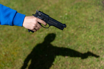 A gun in the hands of a teenager.Child crime.Threatening with a gun in the street.
