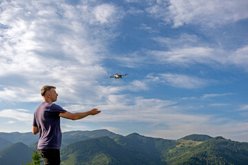 Man flying drone over mountain landscape. A man operates a drone in a scenic mountain area under a...