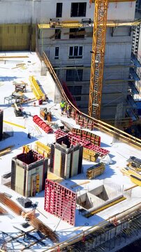 Sunny day at construction site. Workers are actively constructing a building at a construction site with equipment and materials scattered around.